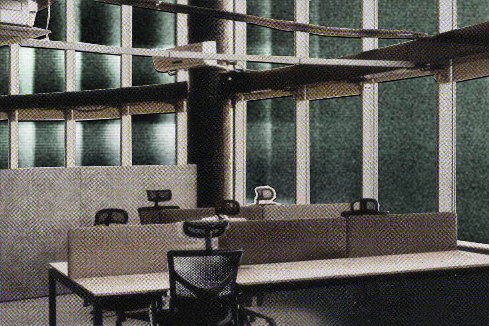 A cut-paper collage. An interior of an grey open-plan office. Cut photographs of rain, rising tides, and protest flicker rapidly in the office windows. The chairs are empty.